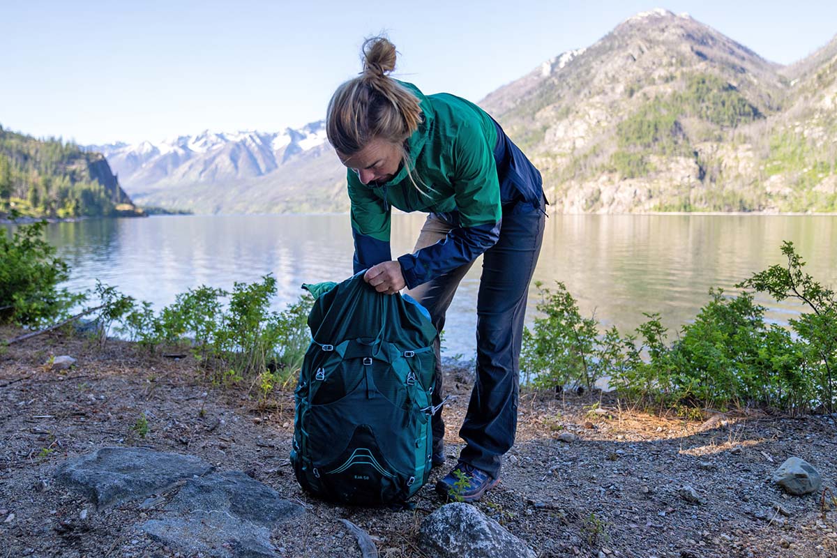Packing pack in camp by lake (Osprey Eja 58 backpack)